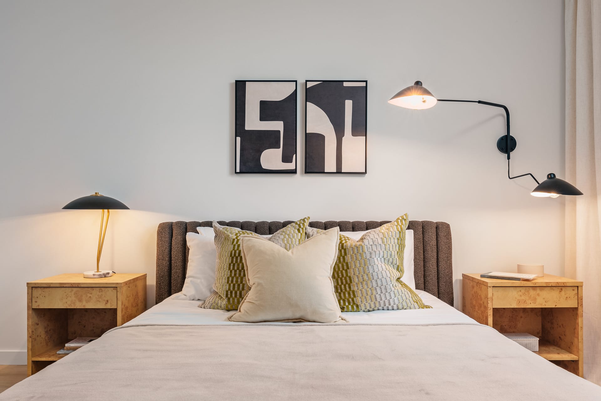 Bedroom at Prisma House with an upholstered headboard, burl-wood nightstands and a pair of framed abstract prints